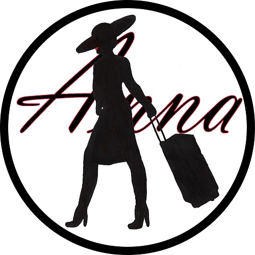 A circular logo with a white background and a thick black outline. In the middle, there is a silhouette of a woman with a wide-brimmed hat tilted forward over her eyes dragging a rolling suitcase behind her. She is wearing a knee-length dress and high-heeled shoes. Her lips are red, but the rest of the silhouette is black. She is superimposed over the word 'Anna' in black script text with a red outline.